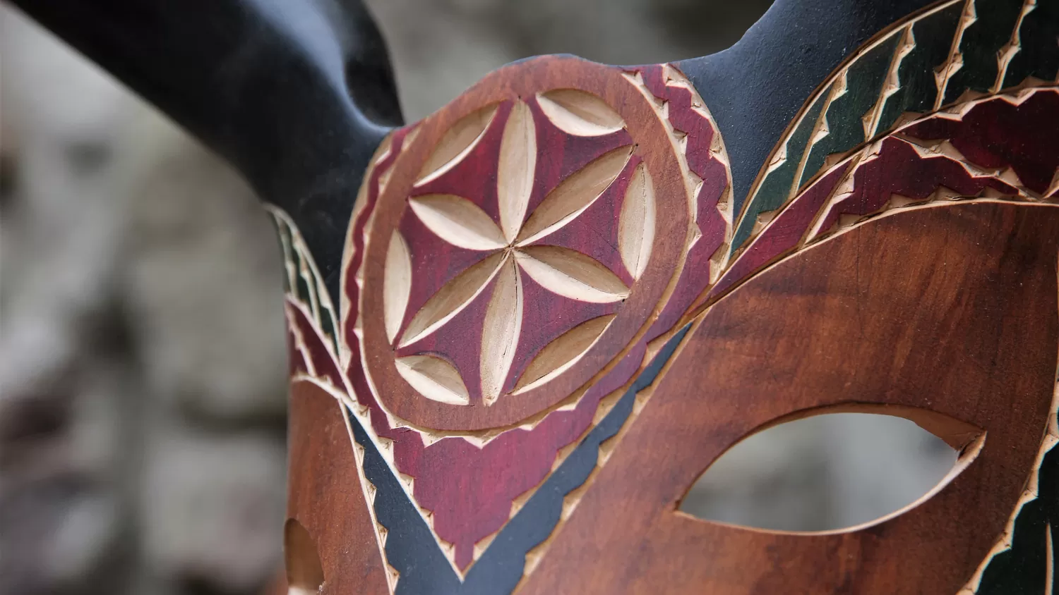 Una maschera di legno intagliata e dipinta a mano, con la rosetta incisa e le corna scure