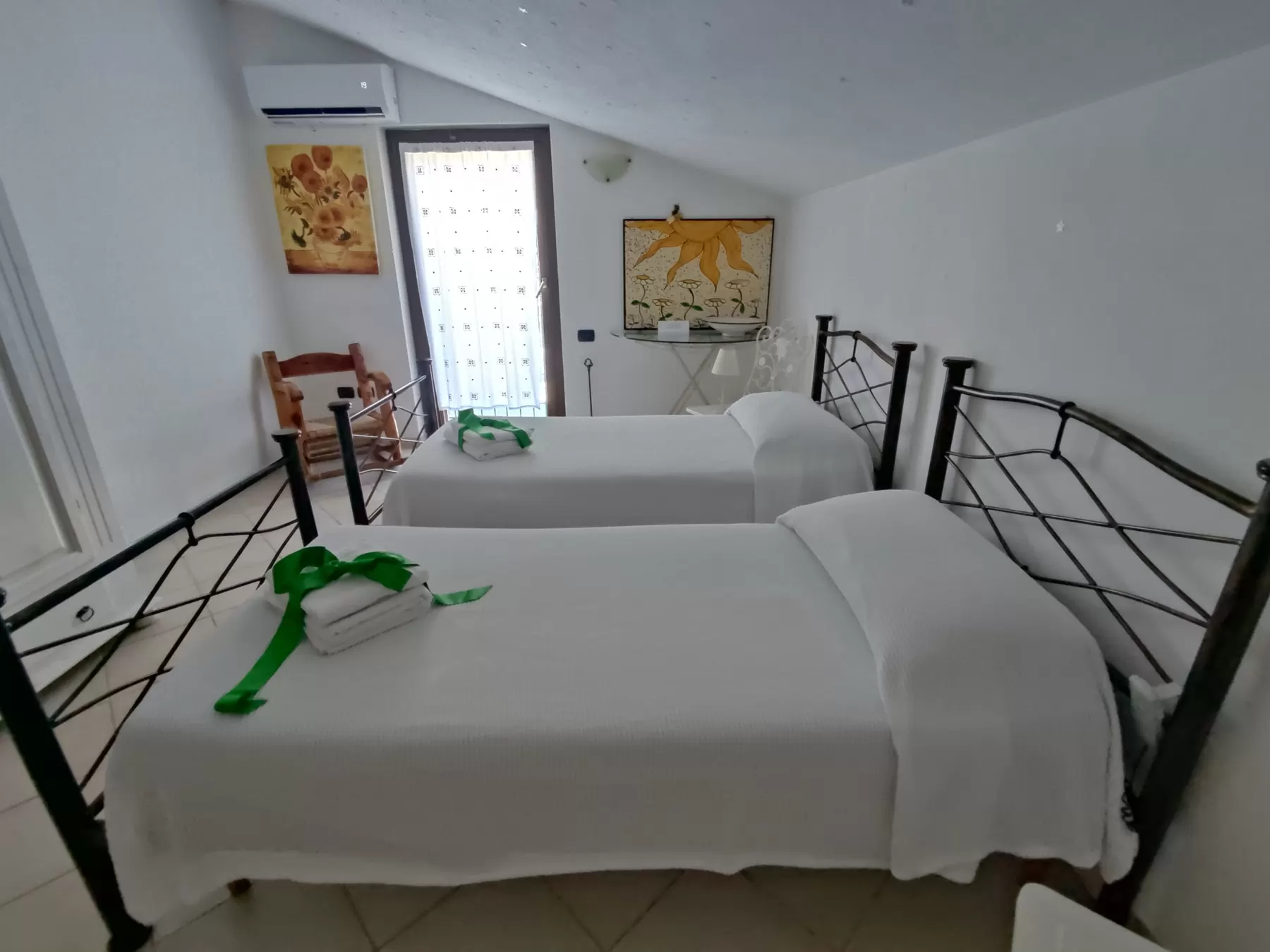 Camera mansardata con soffitto spiovente, due letti singoli, girasoli dipinti alle pareti e stelline sul soffitto