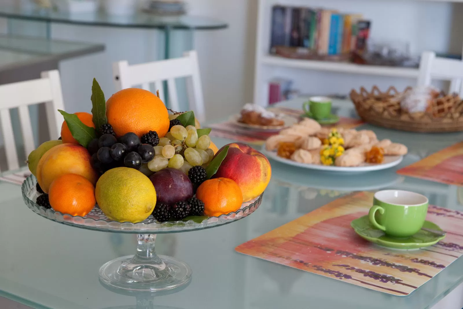 Primo piano dell'alzata di frutta fresca: arance, uva, pesche, prugne e limoni sul tavolo della colazione